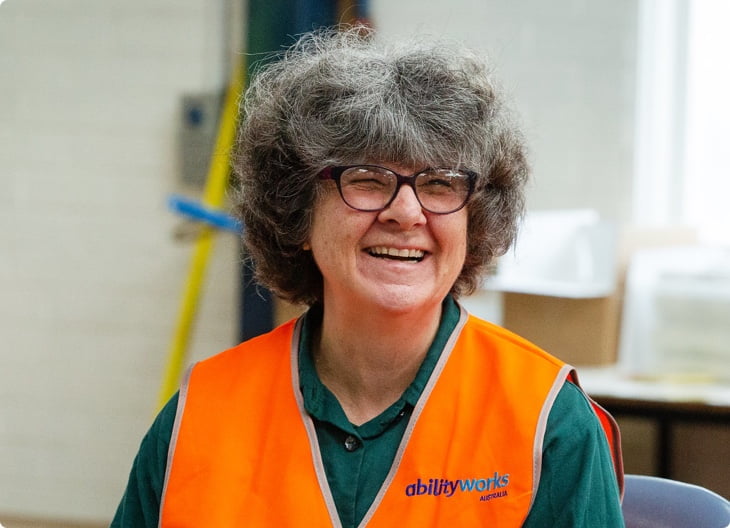 smiling ability works employee wearing an orange high vis vest and glasses