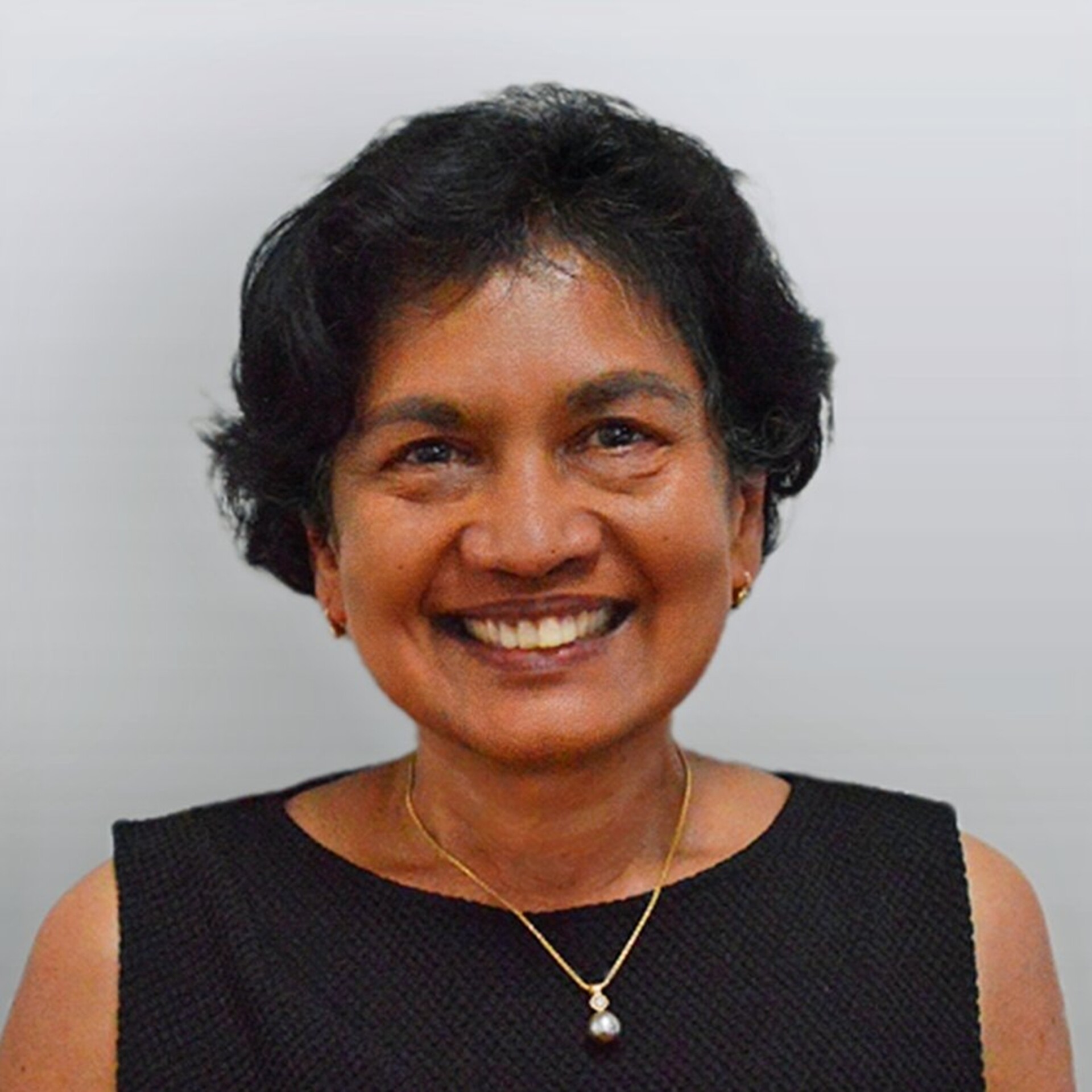 Sue is smiling at the camera; she has short black hair and is wearing a black top.